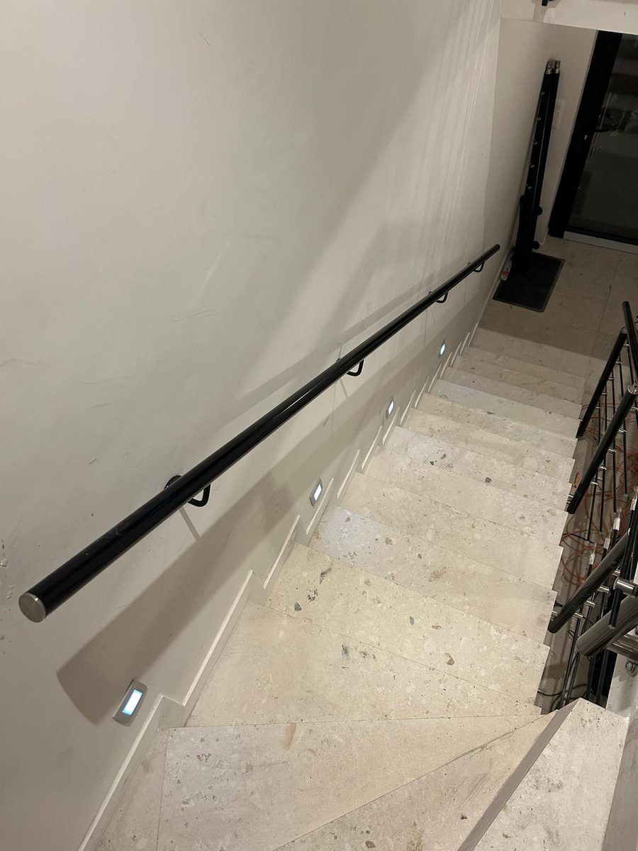 Main courante murale noire sur un escalier intérieur avec spots LED